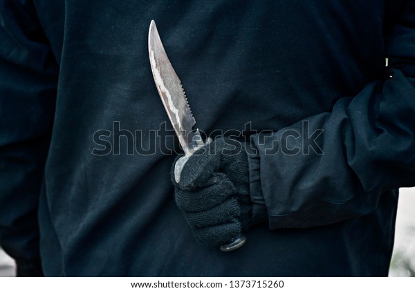 Man with the knife.\
Hand with a knife behind his back. Criminal with knife weapon\
hidden behind his back