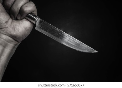 The man with a knife in the hand close up on dark background