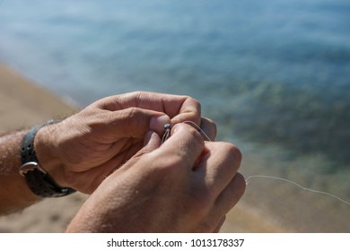 A Man Knots A Fishing Hook And Lead At The Beach