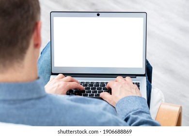 Man with laptop computer on lap working from home or in office with blank screen - Shutterstock ID 1906688869