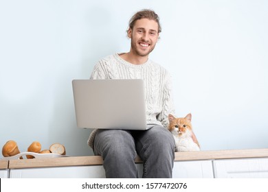 Man With Laptop And His Cute Cat In Kitchen