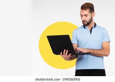 Man With Laptop On A Light Background. Man Works With Laptop While Standing. Portrait Of Young Guy With Laptop Computer. Concept - Sale Of Laptops. Computer Hardware Store. Guy Is Typing Something