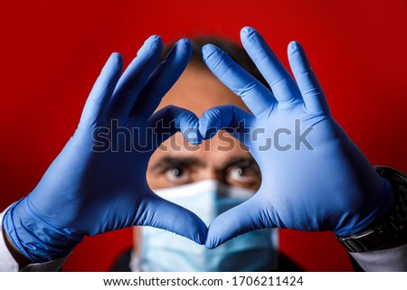 Man with latex gloves forms a heart with his fingers, isolated on a red background