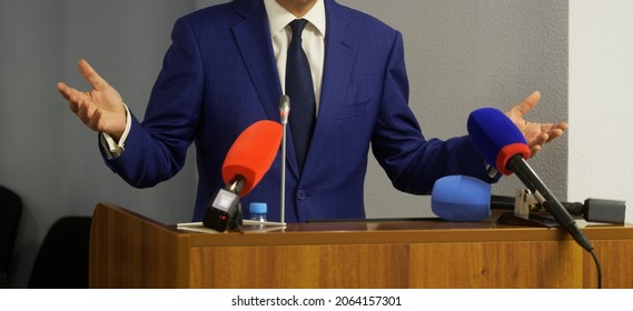 A man - a lawyer, politician, businessman or official speaks from the rostrum in front of microphones. Hand gestures. Speaker or interviewee. No face