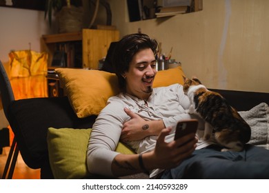 Man Laying In His Room, Using Mobile Phone With Companionship Of His Cat