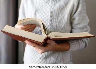 The man is leafing through a huge old book. Selective focus on the book.