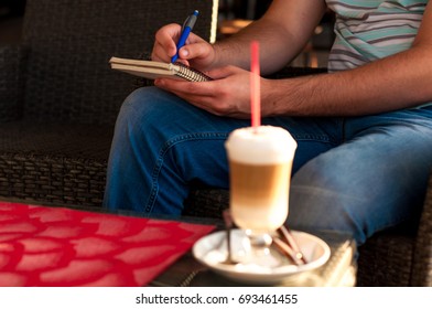 Man leafs through the diary and drinking coffee latte