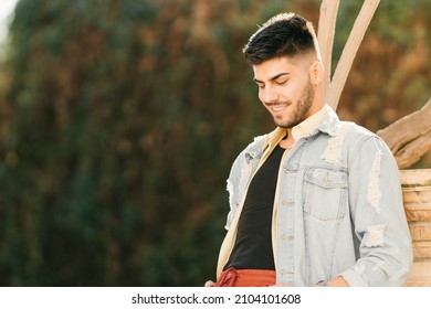 Man Leaning Against A Column In A Park Smiling With A Blank Stare