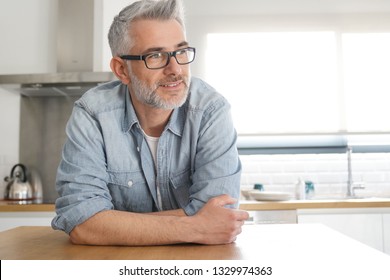 Man leaning on kitchen counter top at home - Powered by Shutterstock