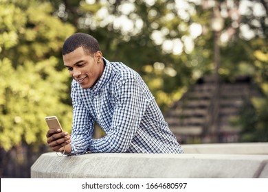 A man leaning on a parapet looking at a smart phone
