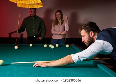 man leaning over the table while playing snooker, he is concentrated on game, having leisure time
