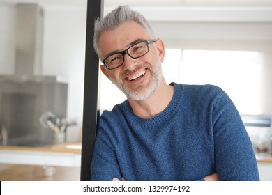 Man Leaning And Smiling At Home In Modern Kitchen