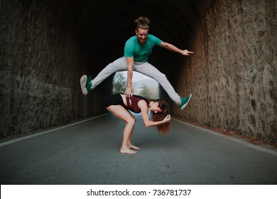 Man Leapfrog Jumping Over Woman On A Road.