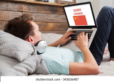 Man learning Chinese on the internet with a laptop computer while lies down at home