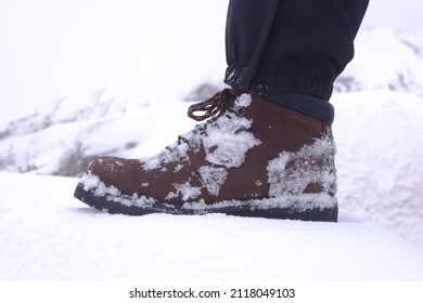 Man With Leather Boot With Snowy Background. Hiking In Winter.