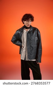 Man in a leather jacket and patterned shirt poses stylishly amid bold colors.