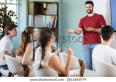 Man lecturer with remote controller provides students with information, provides thematic lesson at business school. Lecture on developing own brand, training for startups, personal growth courses