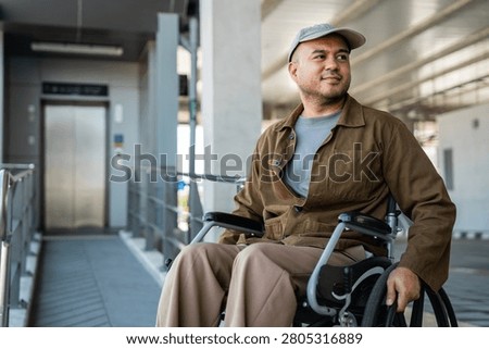 A man with a leg disability who cannot walk uses a wheelchair and travels by the train at a station He walks along the sidewalk where there are signs indicating accessibility for disabled individuals