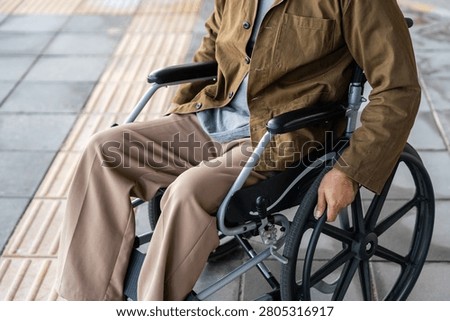 A man with a leg disability who cannot walk uses a wheelchair and travels by the train at a station He walks along the sidewalk where there are signs indicating accessibility for disabled individuals