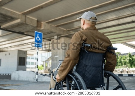 A man with a leg disability who cannot walk uses a wheelchair and travels by the train at a station He walks along the sidewalk where there are signs indicating accessibility for disabled individuals