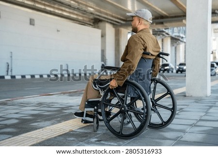 A man with a leg disability who cannot walk uses a wheelchair and travels by the train at a station He walks along the sidewalk where there are signs indicating accessibility for disabled individuals