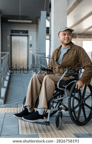 A man with a leg disability who cannot walk uses a wheelchair and travels by the train at a station He walks along the sidewalk where there are signs indicating accessibility for disabled individuals