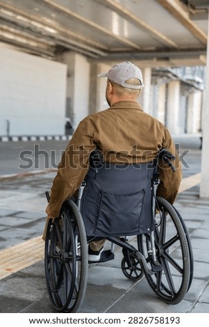 A man with a leg disability who cannot walk uses a wheelchair and travels by the train at a station He walks along the sidewalk where there are signs indicating accessibility for disabled individuals