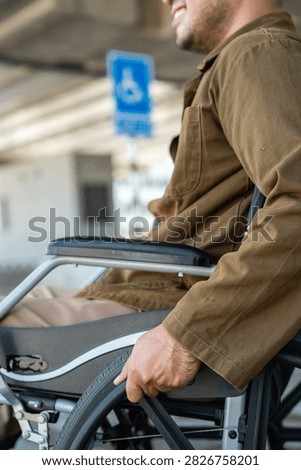 A man with a leg disability who cannot walk uses a wheelchair and travels by the train at a station He walks along the sidewalk where there are signs indicating accessibility for disabled individuals