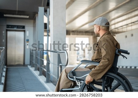 A man with a leg disability who cannot walk uses a wheelchair and travels by the train at a station He walks along the sidewalk where there are signs indicating accessibility for disabled individuals