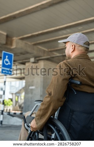 A man with a leg disability who cannot walk uses a wheelchair and travels by the train at a station He walks along the sidewalk where there are signs indicating accessibility for disabled individuals