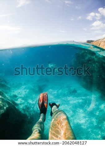 Similar – Unbekannter Jugendlicher in Neoprenanzug und Schnorchel im klaren Wasser mit felsigen Klippen von Menorca, Spanien, geteilter Blick über und unter der Wasseroberfläche