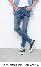 Man Legs Torn Jeans With Sneakers On A White Background. Isolation On Gray Background 

