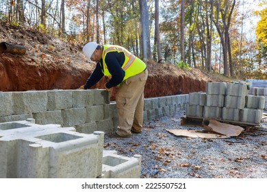 Man levels concrete block wall that is being built on new piece of property as part new retaining wall construction project
