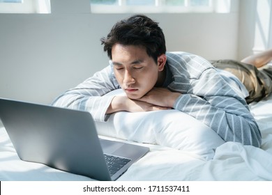 A man lie down on the white bed while he work from home as the company's policy due to disease outbreaks, take a nap after video conference.