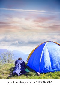 Man Lie In Sleeping Bag Near The Tent