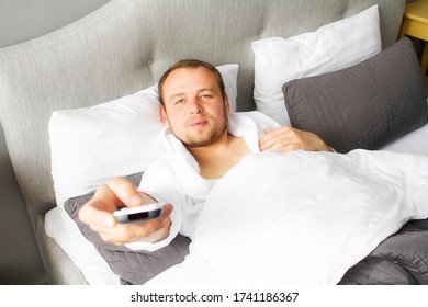 A Man Lies In Bed In The Morning With A Remote Control.