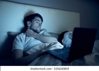 A Man Lies In Bed Next To A Woman Laptop Watching A Movie Night