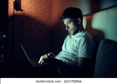 A Man Lies In Bed At Night In Front Of A Laptop Watching A Movie