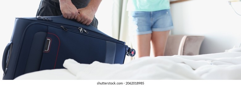 Man Lifting Heavy Suitcase In Front Of Woman In Hotel Room Closeup