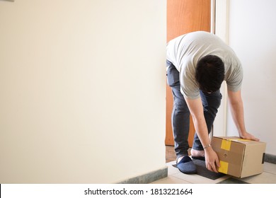 man lifting a package at the door of his house
