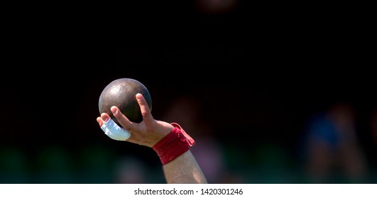 Man Lifting Shot Put at a Track and Field Meet - Powered by Shutterstock