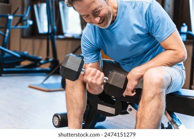 A man is lifting weights in a gym. He is smiling and he is enjoying himself. Concept of positivity and motivation, as the man is working hard to improve his fitness - Powered by Shutterstock