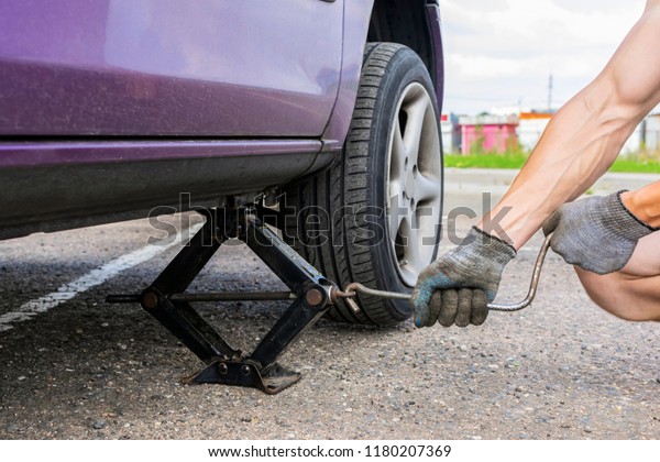 the man lifts the car with a jack. tire\
puncture on the road. wheel\
replacement
