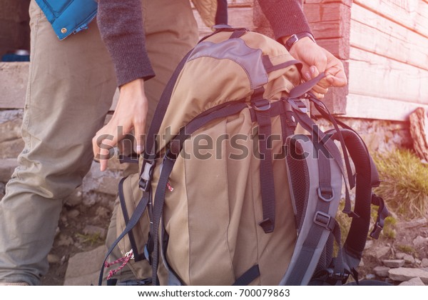 Man\
lifts travel backpack In the mountains.\
close-up.