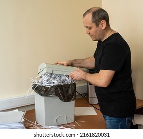 the man lifts the upper cutting part of the shredder. shredder basket filled with cut paper. destruction of confidential information