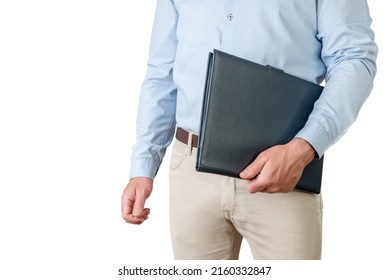 Man In Light Blue Shirt And Beige Pants Holding A Folder Under His Arm On A White Background