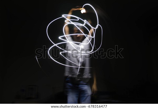Man light painting\
curves in the dark