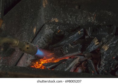 A Man IS Lighting Charcoal With Propane Torch On Home Made Grill Close Up