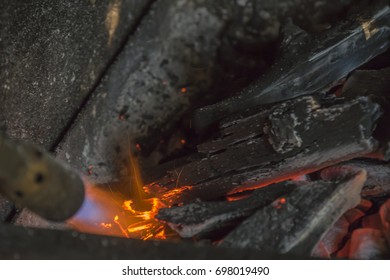 A Man IS Lighting Charcoal With Propane Torch On Home Made Grill Close Up