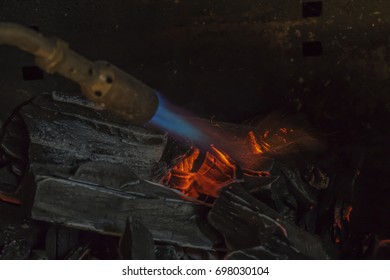 A Man IS Lighting Charcoal With Propane Torch On Home Made Grill Close Up